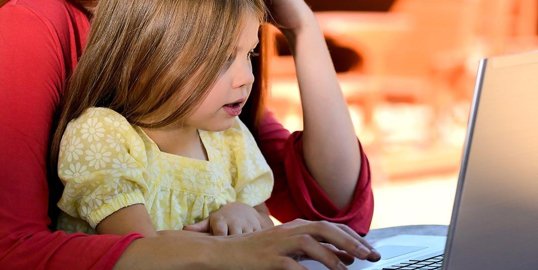 A child and adult using a laptop